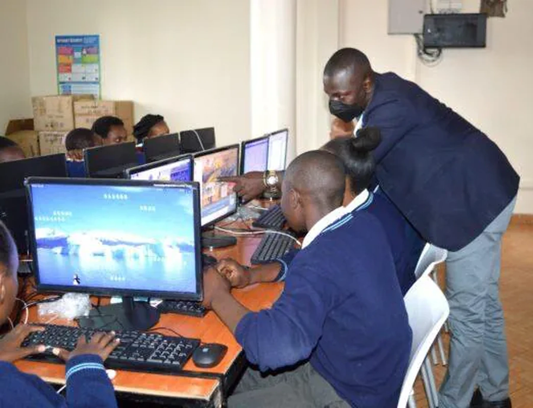 Teacher supporting learners in a computer classroom